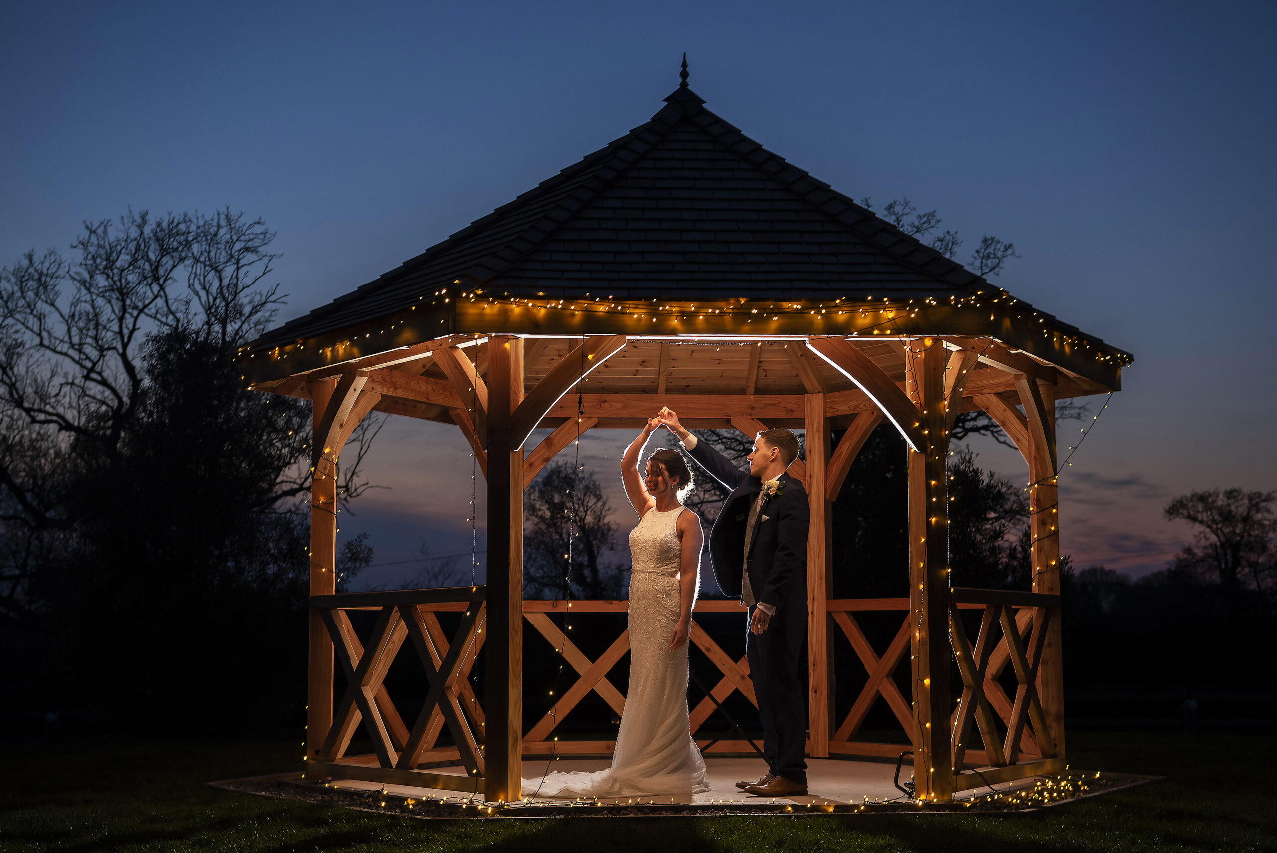 bride and groom dancing in wedding pavilion with fairy lights