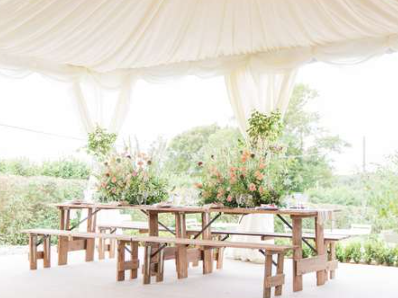 Wedding breakfast set up with rustic tables and flower centerpiece