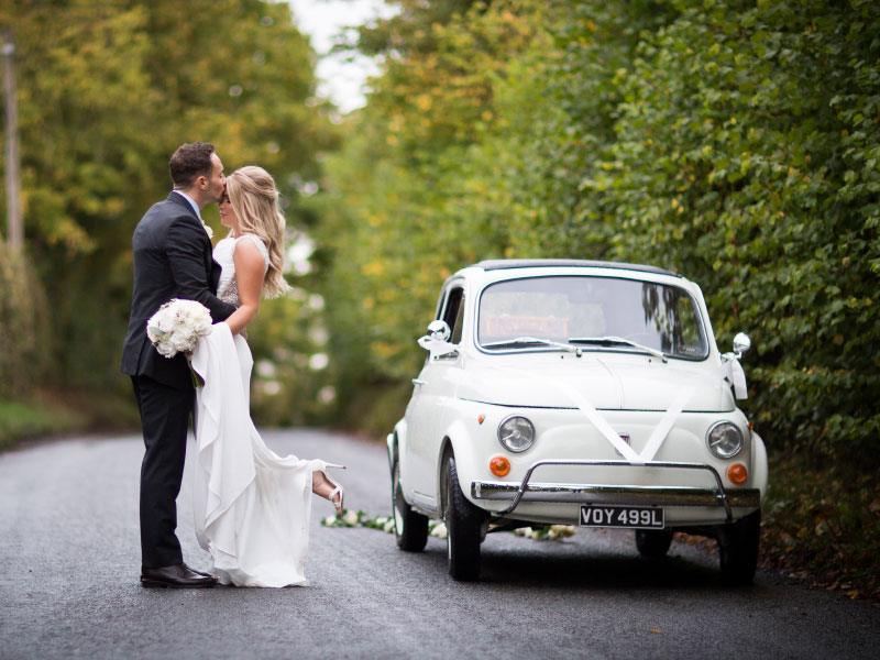 bride and groom with vintage car in the lane