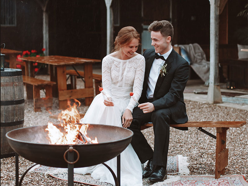 bride and groom toasting marshmallows at fire pit