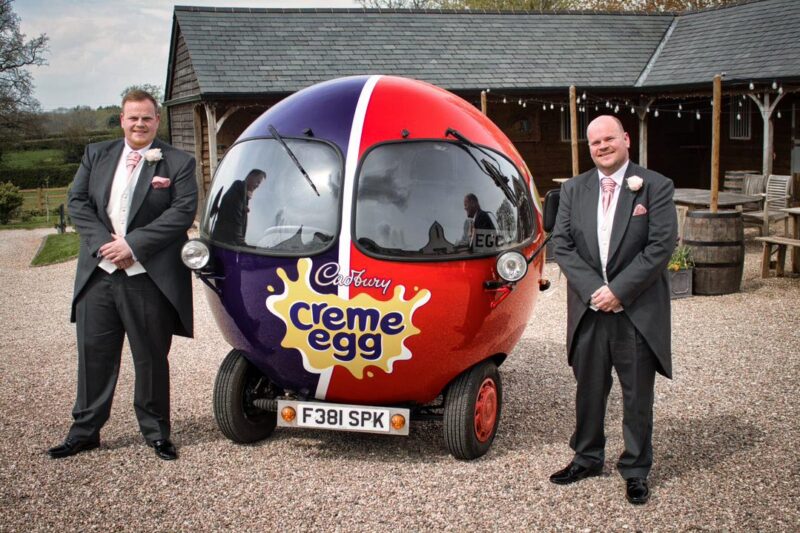 Groom and Best Man stood next to Cadbury Creme Egg Car