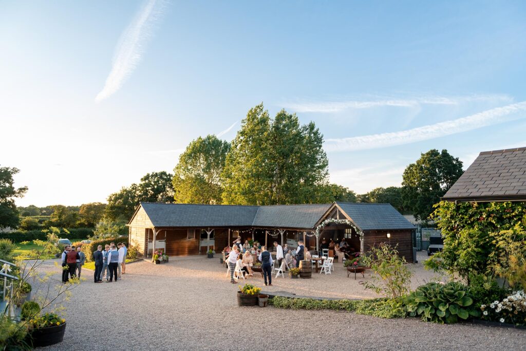 Guests gathering around the stables at an outdoor wedding venue